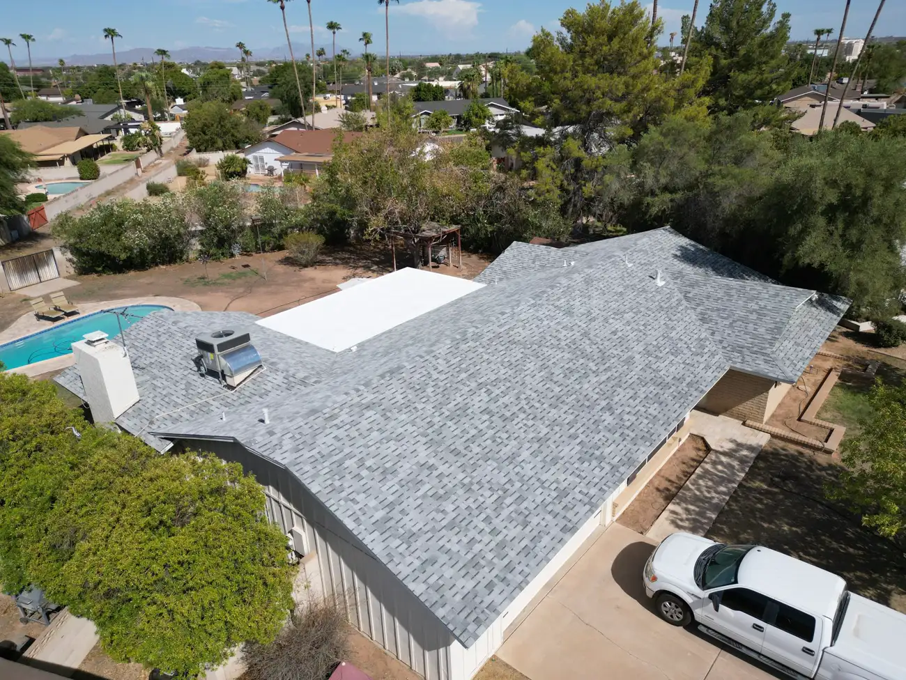 Aerial view of a completed grey shingle roof over a home with a swimming pool, by A1 Roofing Solutions