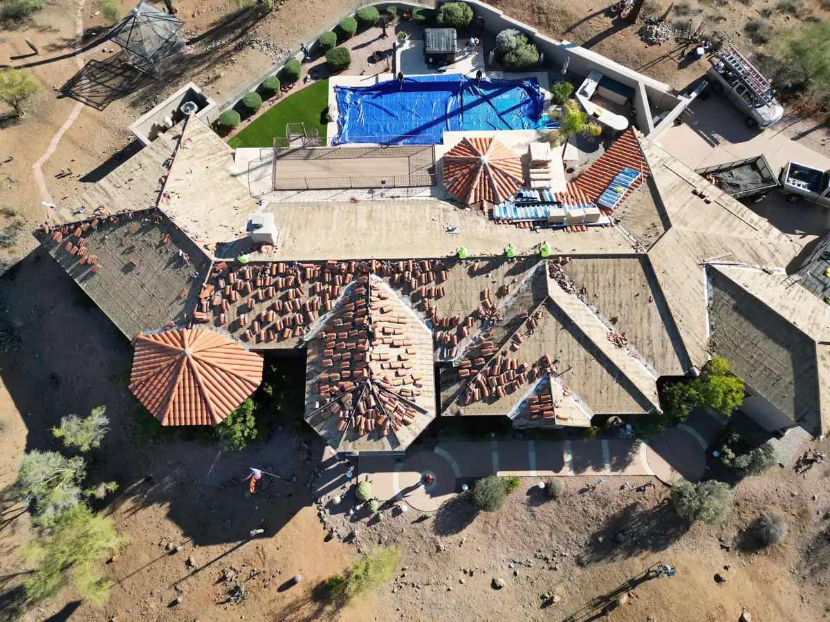 Drone view of an A1 Roofing tear-off in progress, with the old surface stripped and tarps protecting the property