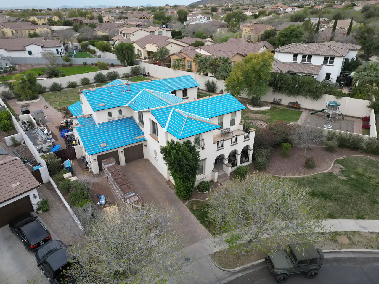Aerial view of a home dried-in by A1 Roofing, underlayment sealed and ready for the finish surface